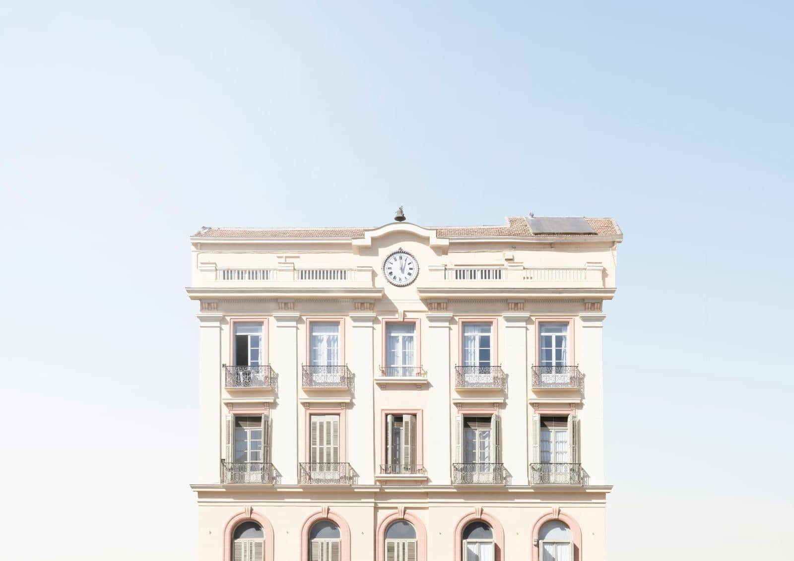 A light-colored building with many windows under a clear sky.